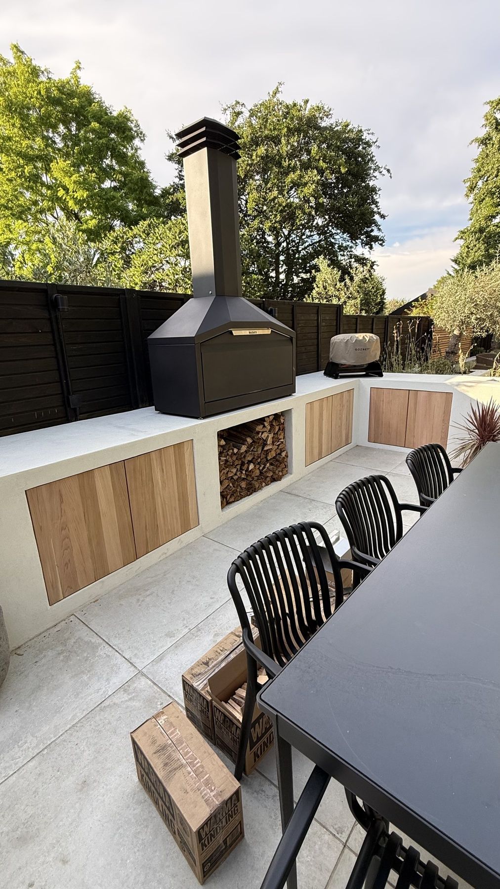 Outdoor kitchen corner with oven, timber doors and stacked logs