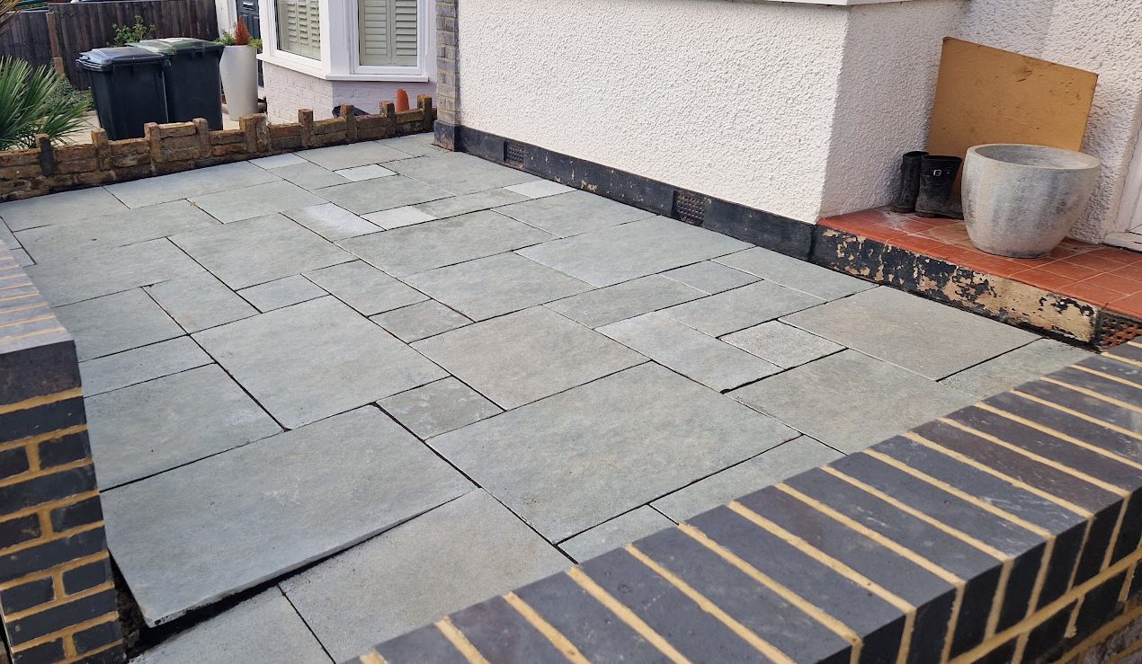 Grey slate front-garden patio inside a new brick wall with a blue-brick coping